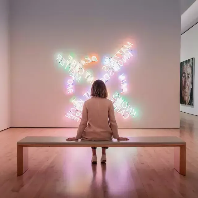 Uma mulher, sentada em um banco, observa uma obra de arte contemporânea de luz no SF MOMA, em São Francisco.